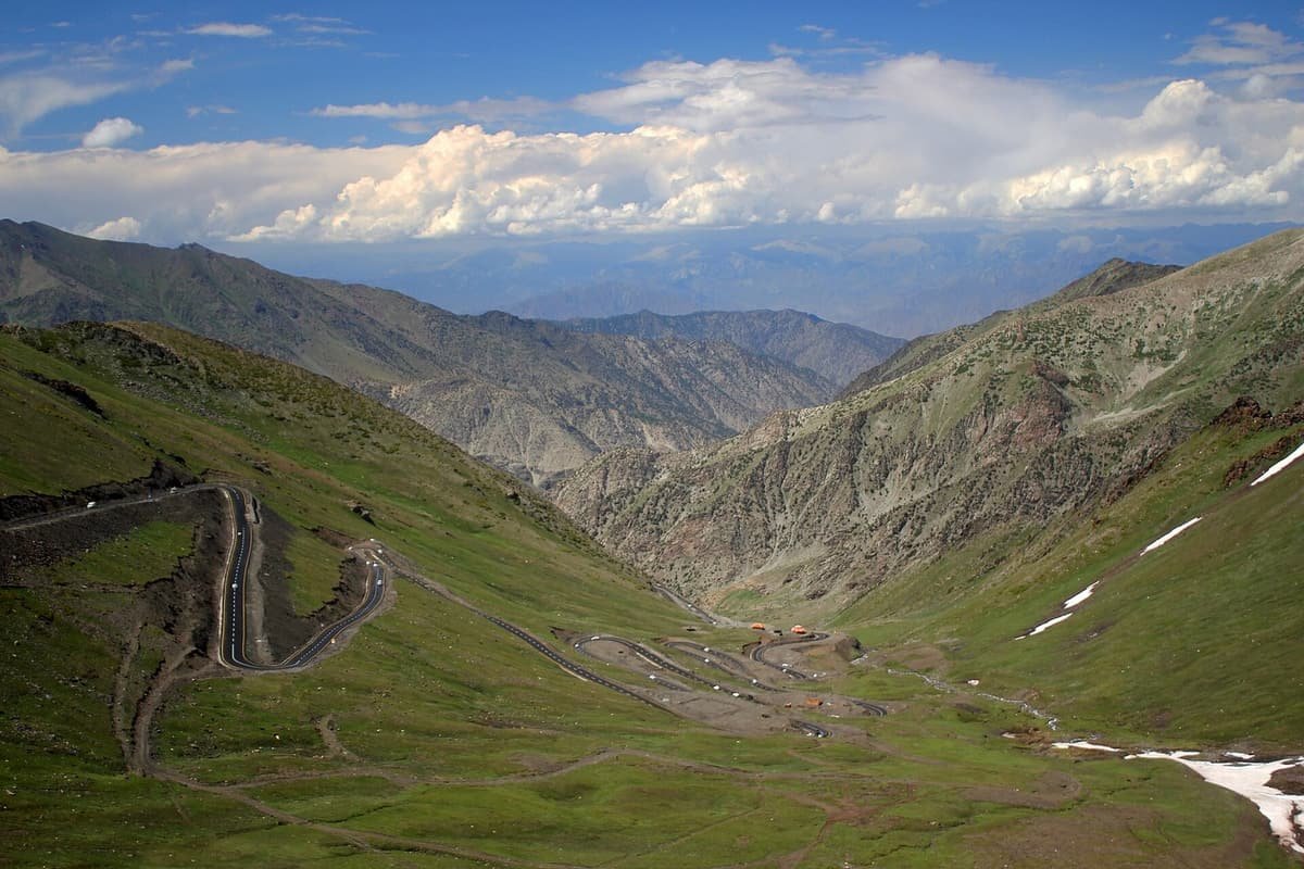 The Babusar road snakes down a green valley in tight hairpins from the pass, between grassy slopes and distant ridges.