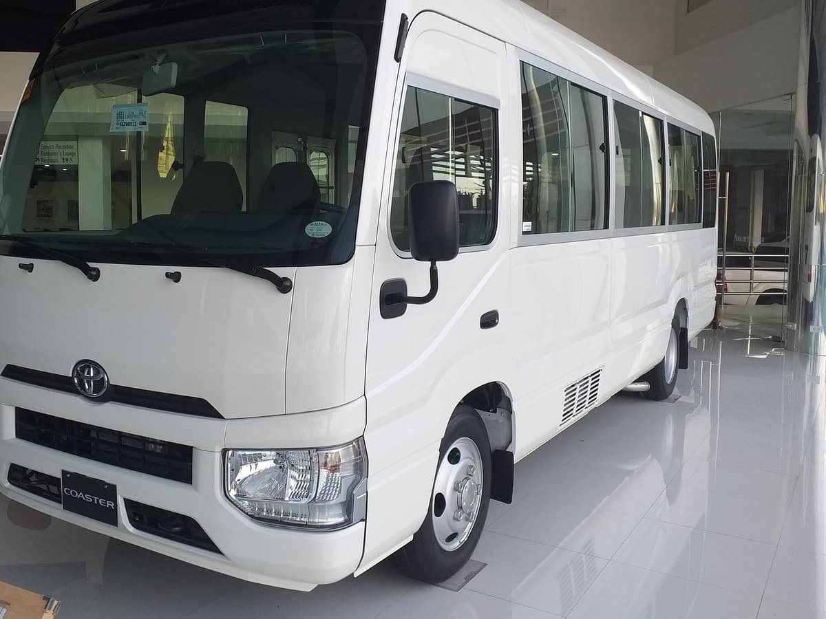 A white Toyota Coaster minibus, seen from the front